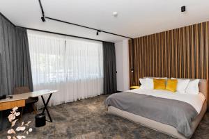 a bedroom with a large bed and a desk and window at MM Boutique Hotel in Burgas