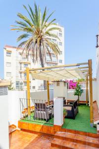 a patio with a canopy and chairs and a palm tree at apartamento con terraza in Valencia