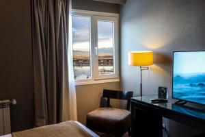 a hotel room with a desk with a television and a window at Alto Andino Hotel in Ushuaia