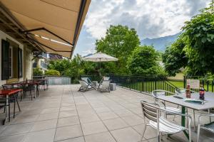 un patio con tavoli, sedie e ombrellone di Chalet Hostel @ Backpackers Villa Interlaken a Interlaken
