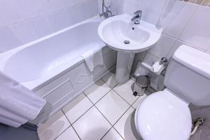 La salle de bains blanche est pourvue de toilettes et d'un lavabo. dans l'établissement Kensington Court Hotel - Earls Court, à Londres
