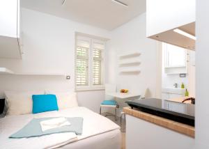 a white bedroom with a bed and a kitchen at Main Square Apartment in Hvar