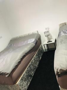um quarto com 2 camas e uma mesa com um candeeiro em Modern Travis House em Burnley