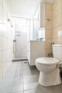 a white bathroom with a toilet and a shower at BeachFront Apt next to the Mall in Heraklio Town