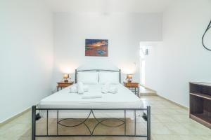 a bed in a white room with two tables at BeachFront Apt next to the Mall in Heraklio