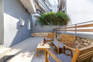 eine Terrasse mit Holzbänken und einem Tisch auf einem Gebäude in der Unterkunft BeachFront Apt next to the Mall in Iraklio