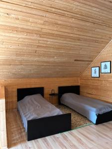 Duas camas num quarto com paredes de madeira em Robadeli Holiday House em Remniku