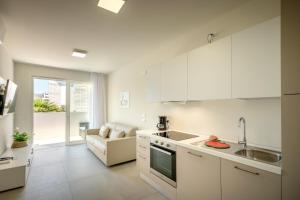 eine Küche mit weißen Schränken, einer Spüle und einer Couch in der Unterkunft Residence MAXIM in Caorle