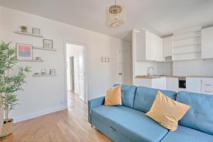 uma sala de estar com um sofá azul e uma cozinha em White & Wood - Charmant appartement pour 4 em Vitry-sur-Seine