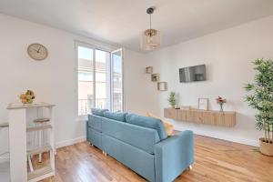uma sala de estar com um sofá azul e um relógio em White & Wood - Charmant appartement pour 4 em Vitry-sur-Seine