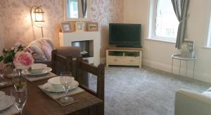 a living room with a table and a television at Clock Tower Flats Morpeth in Morpeth
