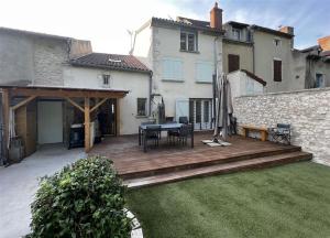 una terraza de madera con mesa y sillas en un patio en Maison terrasse au bord de l'eau, en Ébreuil