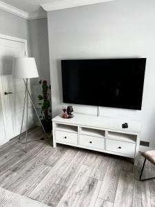 een woonkamer met een wit entertainmentcentrum met een flatscreen-tv bij Modern 2-bed flat in town centre in Oban