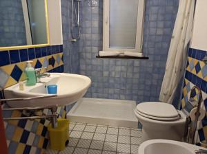 a blue tiled bathroom with a sink and a toilet at CasaGiulia Calasetta in Calasetta