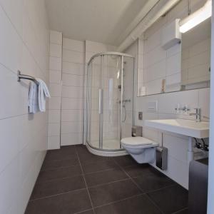 ein Bad mit einer Dusche, einem WC und einem Waschbecken in der Unterkunft Omnium Sport Hotel in Grenchen