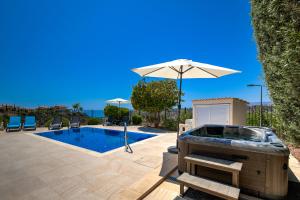 una piscina con ombrellone e vasca idromassaggio di 3 bedroom Villa Melandra with private pool and sea views, Aphrodite Hills Resort a Kouklia