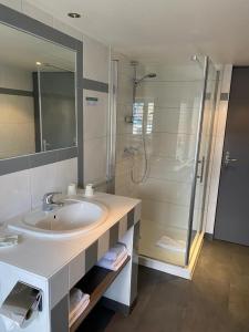 een badkamer met een wastafel en een douche bij Hôtel Saint-Pierre in Pontarlier