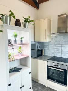 a kitchen with white cabinets and potted plants on shelves at Aplanty Nest amidst the Orchard 