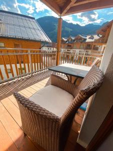 uma cadeira de vime sentada numa varanda com uma mesa em Daniela 3 by SMR Rauris Apartments - inc Spa and National Summercard - near Gondola em Rauris