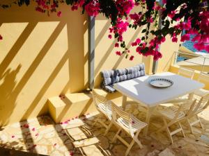 a white table and chairs on a patio with pink flowers at The Cove Assos in Asos +48 photos