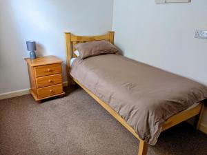 ein Bett mit einem Holzrahmen neben einem Nachttisch in der Unterkunft The White Horse in Linslade