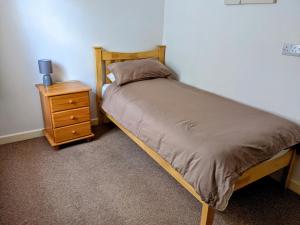 a bed with a wooden frame next to a night stand at The White Horse in Linslade