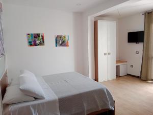 Vianova Affittacamere في جوردينيانو: غرفة نوم بيضاء فيها سرير وتلفزيون