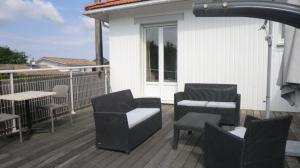 a deck with chairs and tables on a house at Hôtel Le Boïate in Arès