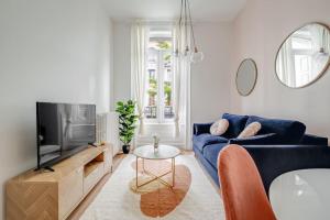 a living room with a blue couch and a tv at Magnifique appartement Blush refait à neuf in Saint-Étienne