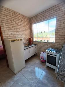 a kitchen with a stove and a sink and a window at hospedagem recanto do sábia 4 in Alto Caparao