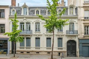 a large white building with a tree in front of it at Magnifique appartement Blush refait à neuf in Saint-Étienne