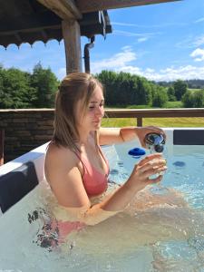 una mujer en un jacuzzi con una copa de vino en Gîte Les 3 pierres, en Houffalize