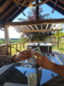 una pareja bebiendo vino en una mesa con vistas en Gîte Les 3 pierres, en Houffalize