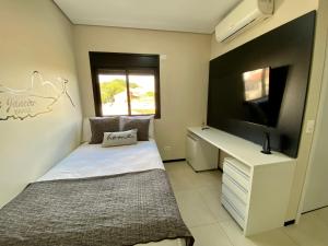 Schlafzimmer mit einem Bett, einem Schreibtisch und einem TV in der Unterkunft 32A Estudio perto do HC in Marília