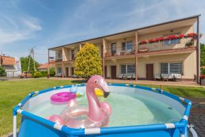 a swimming pool with a pink swan in front of a house at Pokoje i Domki Nadmorskie - Bajkowa Mierzeja in Stegna