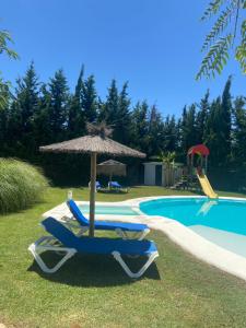 - un parasol et des chaises à côté de la piscine dans l'établissement Chalet Brisas del Mar, à Chiclana de la Frontera