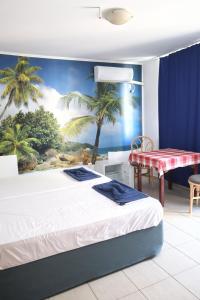 a bedroom with a bed and a palm tree mural at Къща за гости "Arawana" in Sunny Beach
