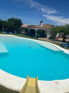 a large blue swimming pool with a yellow object in front of a house at Chalet Brisas del Mar in Chiclana de la Frontera