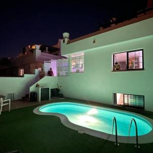 a swimming pool in front of a house at night at Long Beach Surf House in Corralejo