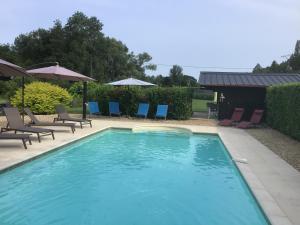 una piscina con sillas y sombrillas azules en Le Moulin de Mayence, en Plazac