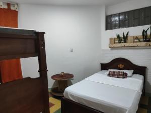 Serrania Hostal في ميديلين: غرفة نوم صغيرة مع سرير وطاولة