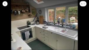a kitchen with a sink and a stove and windows at Central Truro! Large Double Room In Victorian Property in Truro