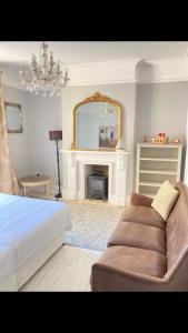 Central Truro! Large Double Room In Victorian Property في ترورو: غرفة نوم بسرير واريكة ومرآة