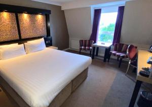 um quarto de hotel com uma cama grande e duas cadeiras em Flannery's Hotel em Galway