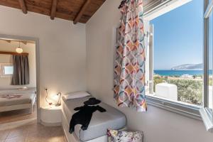 een slaapkamer met een bed en een groot raam bij Michalios Luxury Apartments in Koufonisia