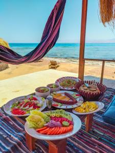 a table with several plates of food on the beach at Flight Mode Camp in Nuweiba