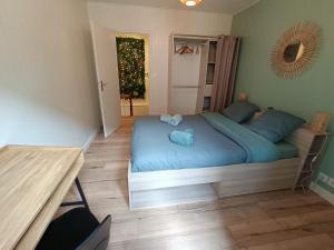 Schlafzimmer mit einem Bett mit blauer Bettwäsche und einem Tisch in der Unterkunft Joli cocon en hyper centre in Loudéac