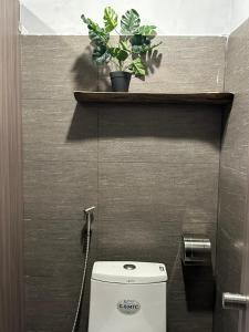 a bathroom with a toilet with a plant on a shelf at T Zone Hostel in Ho Chi Minh City
