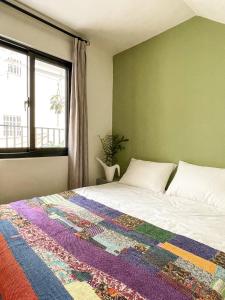 a bedroom with a bed with a colorful blanket on it at Good Trip Hostel 菇憩民宿 in Hengchun
