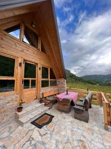 a wooden cabin with a table and chairs on a patio at Vikendica GORSKI VUK Jelovica in Berane